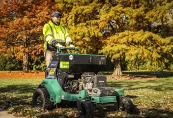 lawn care technician on a green riding lawn mower